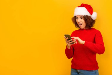 Afrika kökenli Amerikalı bir kadının cep telefonunda büyük noel satışları ya da turuncu arka planda piyango kazanmasıyla ilgili mesaj okuması hoş bir sürpriz oldu. İyi haberler, indirimler, online alışveriş konsepti.