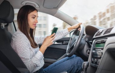 Şehirde yüksek hızda araba kullanırken cep telefonu ekranına bakan kadın