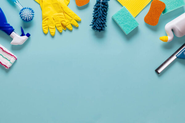 Different cleaning supplies on a blue background with copy space top view