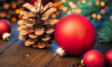 Kır kozalaklı el yapımı Noel dekoru, kırmızı toplar ve ahşap masa üzerinde fotokopi alanı olan rahat bokeh ışıkları.