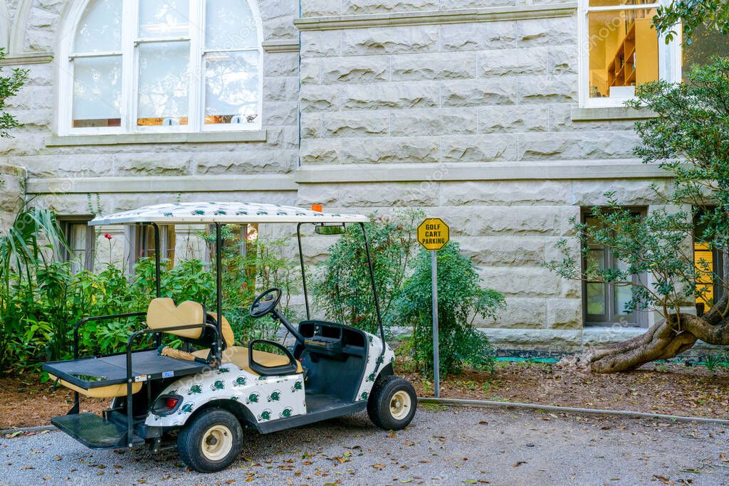 NEW ORLEANS, LA, USA - DECEMBER 9, 2022: Golf cart covered in Green Wave decals parked in designated parking lot behind the administration building on the Tulane University campus