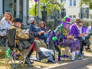 NEW ORLEANS, LA, USA - FEBRUARY 13, 2024: Diverse group of women sitting in folding chairs on St. Charles Avenue wait for the Rex Parade on Mardi Gras day. clipart