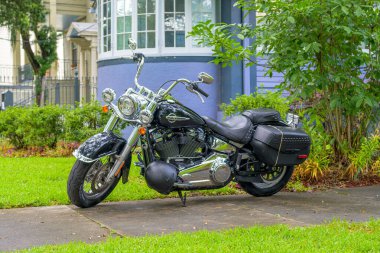 NEW ORLEANS, LA, USA - JUNE 16, 2024: Black Harley-Davidson motorcycle parked on residential walkway in Uptown Neighborhood clipart