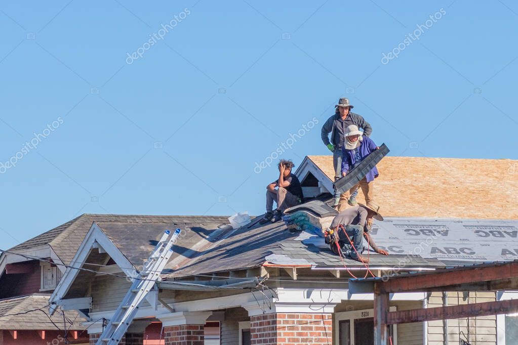 NEW ORLEANS, LA, USA - SEPTEMBER 23, 2021: Four workers repair a roof of a modest home in Uptown Neighborhood