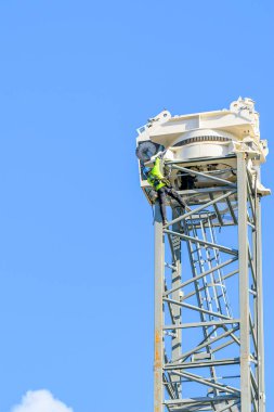 NEW ORLEANS, LA, ABD - 9 ARALIK 2023: Loyola Üniversitesi kampüsündeki bir inşaat projesinin arka planında gökyüzü olan bir kulenin tepesinde inşaat işçileri.