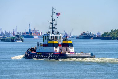 NEW ORLEANS, LA, USA - SEPTEMBER 29, 2024: Selective focus of Tractor Tugboat Liz Healy moving downriver with cargo ships and barges blurred in the background on the Mississippi River clipart