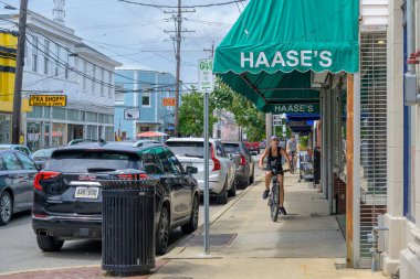 NEW ORLEANS, LA, USA - AUGUST 31, 2024: Woman and Man riding their bicycles on the sidewalk in a business community on oak street in violation of city ordinance clipart