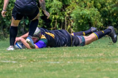 New Orleans, LA, USA - September 14, 2024: Rugby player with ball laid out on the ground after being tackled in a free and open rugby match in City Park clipart