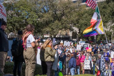 New Orleans, LA, ABD - 17 Şubat 2025: Megafonlu Kadın, demokrasiyi desteklemek ve Donald Trump ve Elon Musk 'a karşı çıkmak için Başkanlık Günü' nde işaretler ve bayraklarla toplandı.