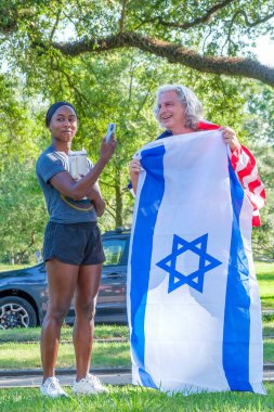 New Orleans, LA, ABD - 24 Haziran 2024: St. Charles Bulvarı 'nda Filistin yanlısı bir gösteriye karşı çıkan beyaz adamın elinde İsrail bayrağı tutan Afrikalı Amerikalı kadın videoları