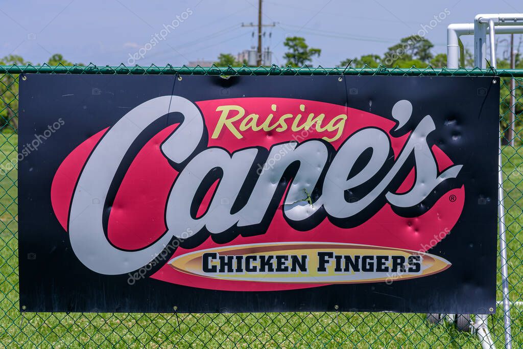 New Orleans, LA, USA - May 1, 2025: Closeup of Raising Cane's Chicken Fingers sign on an outfield fence at a youth baseball park in Uptown Neighborhood