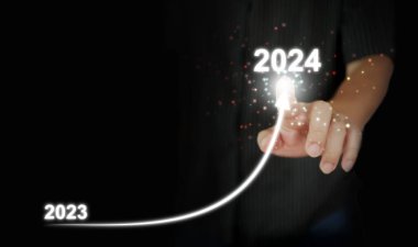 A man's finger draws an upwards curved line from 2023 to 2024. New Year, Christmas, start-up, new business, setting a personal goal