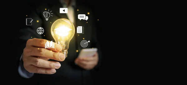 Hand of a businessman holding a glowing lightbulb, symbolizing his innovative and new ideas.