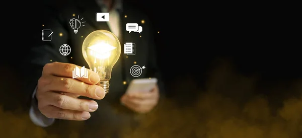 Hand of a businessman holding a glowing lightbulb out of foggy environment. Symbolizing his innovative and new ideas.