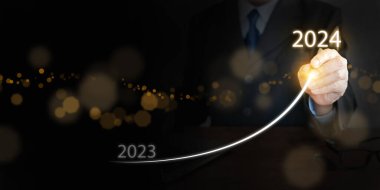 Bir işadamı, 2023 'ün sonundan 2024' ün başına kadar sanal ekranda yükselen bir eğri çiziyor. Mutlu yıllar ve yeni iş hedefleri ve vizyonlara hoş geldiniz. 