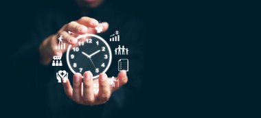 Zaman yönetimi konsepti. Ellerinde saat ve zaman ile ikonları yöneten bir adam hayatını, işini, verimlilik için çalışmasını teknolojiyi kullanarak planlıyor.