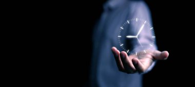 Zaman yönetimi konsepti. Elinde saati olan bir adam teknolojiyi kullanarak hayatını, işini ve verimlilik için çalışmasını yönetip planlamaya dikkat ediyor.