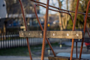 Çocukların salıncakları akşam güneşinde bir oyun bahçesinde sallanıyor.