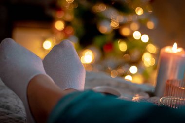 Şöminenin arka planında Noel süsleri olan kadın.