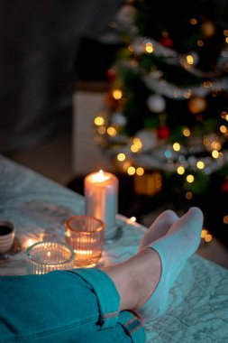 Şöminenin arka planında Noel süsleri olan kadın.