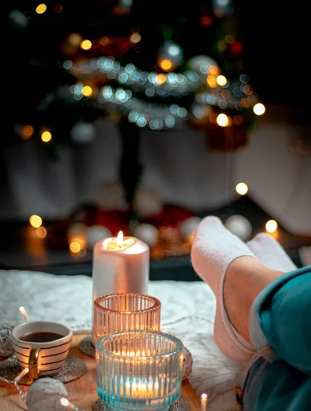christmas candle in the hands of a woman in the background of the fireplace