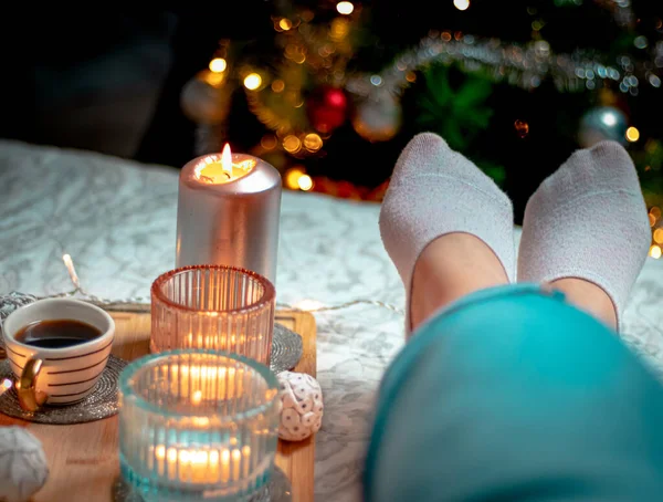 Bir fincan kahve ve noel ağacını ahşap masada tutan kadın.