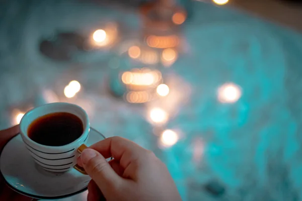 cup of coffee with a red candle on a wooden table.