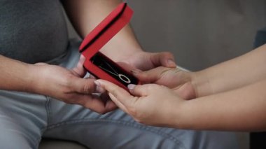 A man gives a gift to a girl a gold jewelry, a red box with a gold chain for a girl, valentine's day, valentine's day gifts