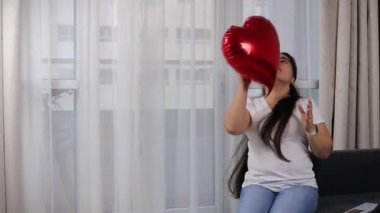 woman playing with heart shaped balloon, valentine's day