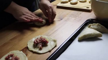 female hands put minced meat filling in puff pastry, homemade food, samsa making, traditional uzbek food
