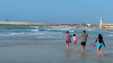 people at the beach in the sea, the sun is a large family on the sandy shore