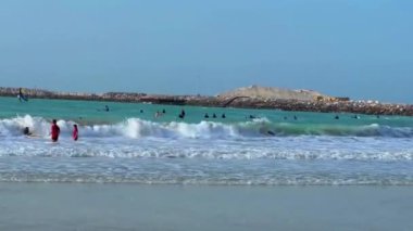beach view of sea, ocean, waves, sandy shore, white and turquoise water, blue skies in
