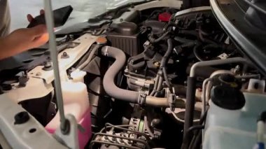 Bir adam arabanın motorunu kontrol ediyor.