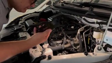 Bir adam arabanın motorunu kontrol ediyor.