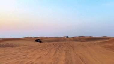 Dubai yakınlarındaki çölde dört tekerli bisiklet turu. ATVSand ve Sand Borkhan 'daki çöl off-road maceraları. Kaya ve gün batımı. Dörtlü Bisiklet Seyahati. İnsanlarla bir gezi. Yüksek kaliteli FullHD görüntüler