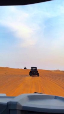 Dubait yakınlarındaki çölde dörtlü bisiklet sürme. ATV ve Sand Borkhan 'daki çöl off-road maceraları. Kaya ve gün batımı. Dörtlü Bisiklet Seyahati. İnsanlarla bir gezi. Yüksek kaliteli FullHD görüntüler