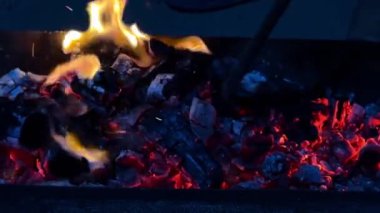 Şöminede sıcak, kırmızı, yakıcı ateş, yakın çekim. Şenlik ateşi enerji yayar, kötü düşünceleri ve olumsuzluğu siler, yenilenme ve yeniden doğuş hissini getirir. Şöminede parlak alevler, yanan odunlar.