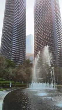 Şehir çeşmesi, gündüz manzarası, binalar arasında güneş ışığı, şehirdeki yüksek binalar.