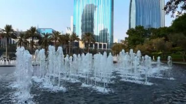 Şehir çeşmesi, gündüz manzarası, binalar arasında güneş ışığı, şehirdeki yüksek binalar.