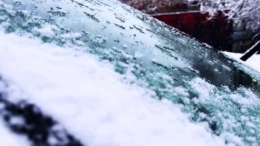 Gün boyunca arabanın ön camına kar yağar, arabanın üstüne kar yağar. Yüksek kalite 4k görüntü