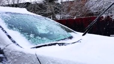 Gün boyunca arabanın ön camına kar yağar, arabanın üstüne kar yağar. Yüksek kalite 4k görüntü