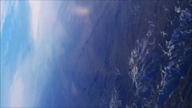 Dağ manzarasının üstündeki kanadın üstündeki uçak penceresinden manzara. Yüksek kalite 4k görüntü