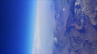 Dağ manzarasının üstündeki kanadın üstündeki uçak penceresinden manzara. Yüksek kalite 4k görüntü