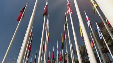 Mavi gökyüzünün arka planında farklı ülkelerin bayrakları.