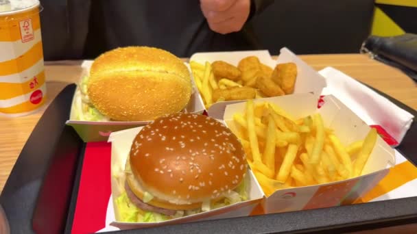 マクドナルドレストラン 不健康なファーストフードを食べる家族 マクドナルドのロゴボックスフライドポテト コーラ — ストック動画