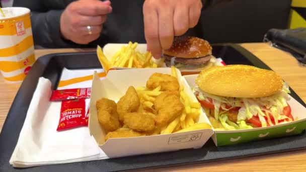 マクドナルドレストラン 不健康なファーストフードを食べる家族 マクドナルドのロゴボックスフライドポテト コーラ — ストック動画