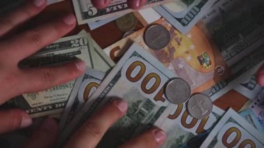 Bu kişi bir yığın para ve para tutuyor, parmakları ve başparmağıyla parayı tutuyor. Para birimi dolar cinsinden, birikimleri temsil ediyor.
