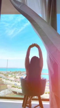 Genç bir kadın otelin balkonunda oturuyor..