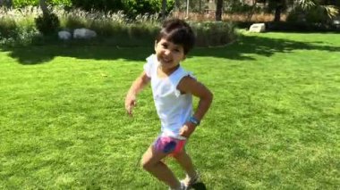 Çocuk oyun oynuyor, küçük kız parkta oynuyor, kız bahçede yürüyor ve koşuyor, küçük kız çimenlerde oynuyor.
