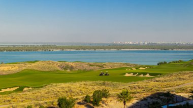 Yeşil çimenli ve mavi gökyüzü olan golf sahası